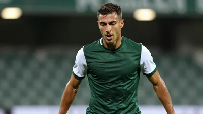 Mid-30s muscular Cercle Brugge midfielder, intense focus, eyes locked on the ball, dark green shirt with white sleeves...