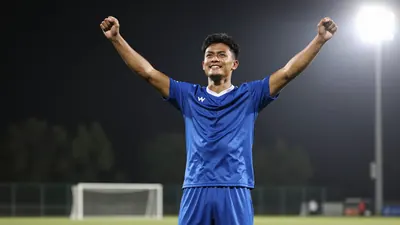 Athletic male football player in a solid blue shirt and shorts, celebrating a goal with arms raised, skin and fabric texture