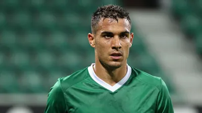 Mid-30s athletic Cercle Brugge midfielder, muscular, short dark hair, intense eyes, head-and-shoulders shot, drenched in...