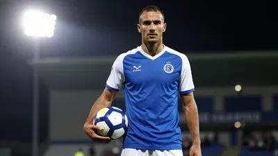 A photorealistic image of an anonymous Cercle Brugge player, aged 25-30, wearing a blue jersey with white sleeves and a...