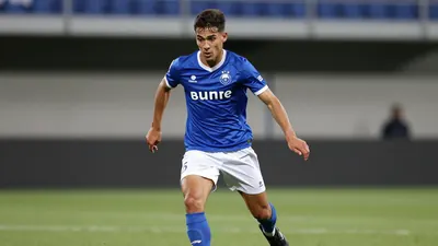 A photorealistic image of a 20-year-old Cercle Brugge player, wearing a blue jersey with white shorts and black boots...