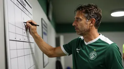 A 35-year-old Cercle Brugge assistant coach, wearing a plain, unmarked dark green and white polyester home kit, his face...